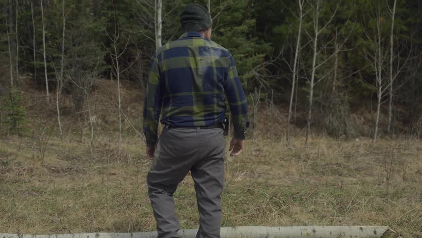 A man covered in dirt lifts a log then drops it