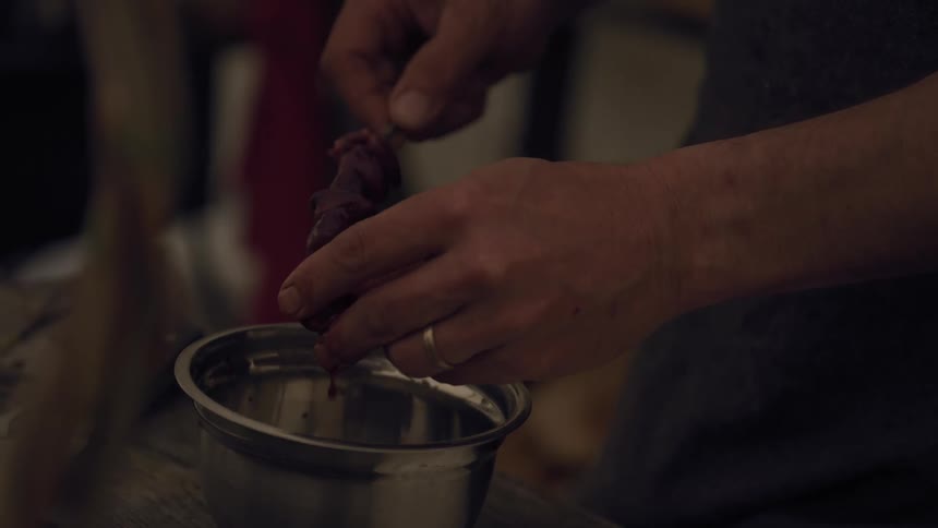 A man puts pieces of meat on a wooden skewer