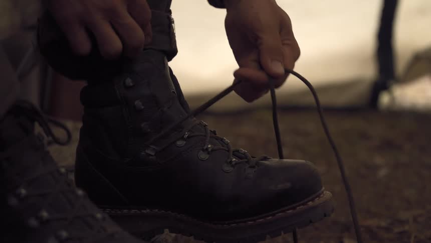 A person is tying their shoe laces outdoors