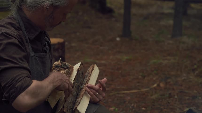 Man placing split wood into campfire in the wilderness