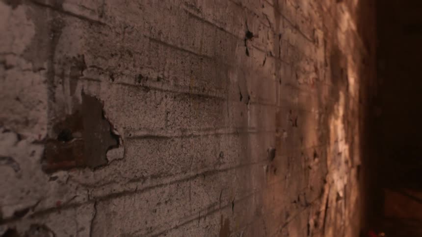 Light shines on a dilapidated concrete wall
