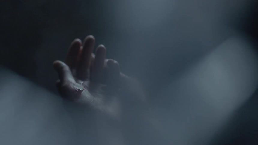 A person opens their cut hands in a dark room