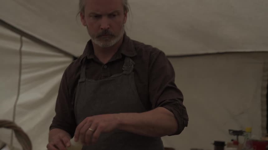 A man pours sauce on the meat in the tent