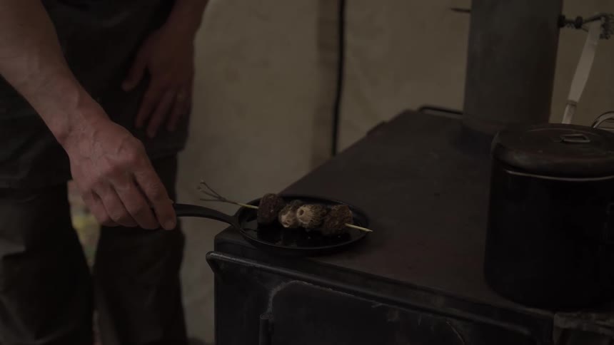 A man cooks morel mushrooms over a stove