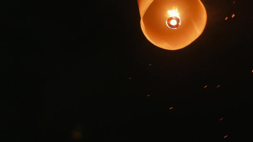 A man sending off a lit lantern/kite