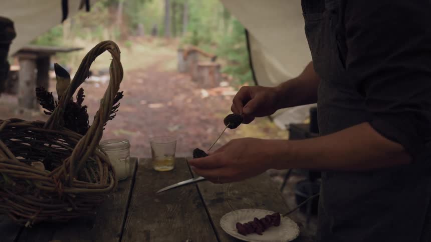 A man is putting food on a skewer in the tent
