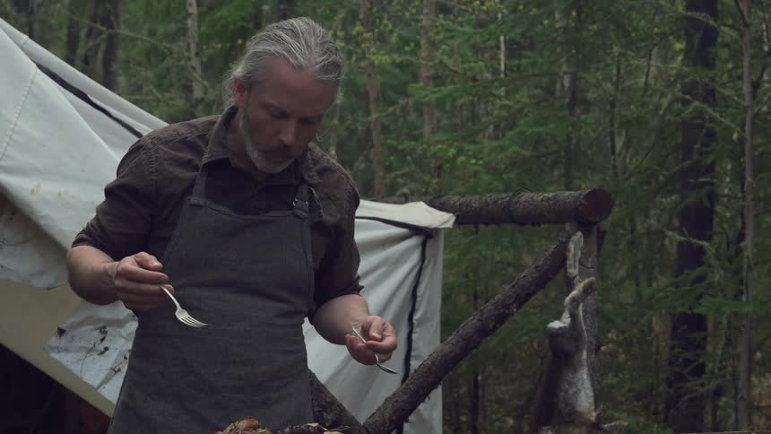 A man is eating food by his tent