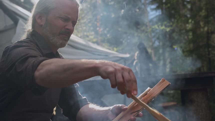 A man adds wood to the campfire