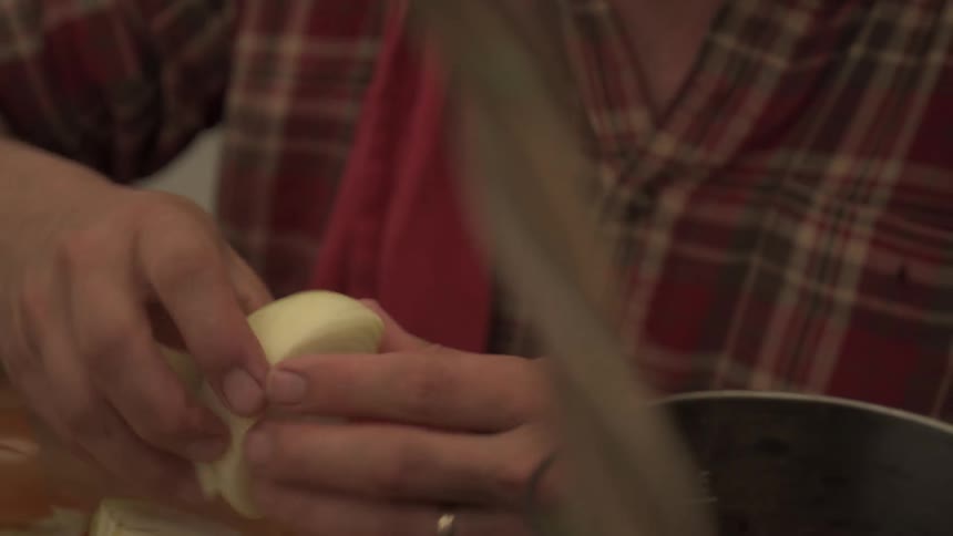 Cutting an onion in quarters with a knife and placing in a small pot