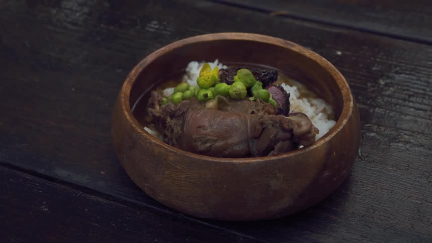 A bowl of food with meat and vegetables is on a table