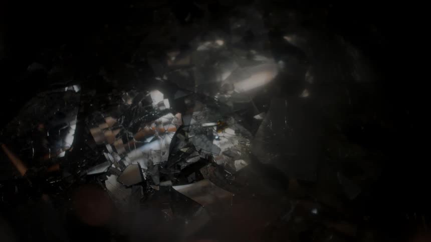 Rays of light shine off a broken mirror on the ground