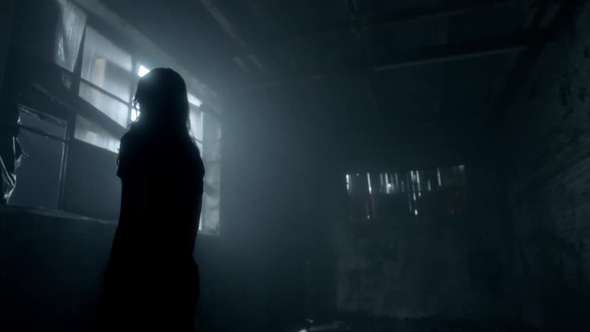 A woman in a rundown building staring out a covered window