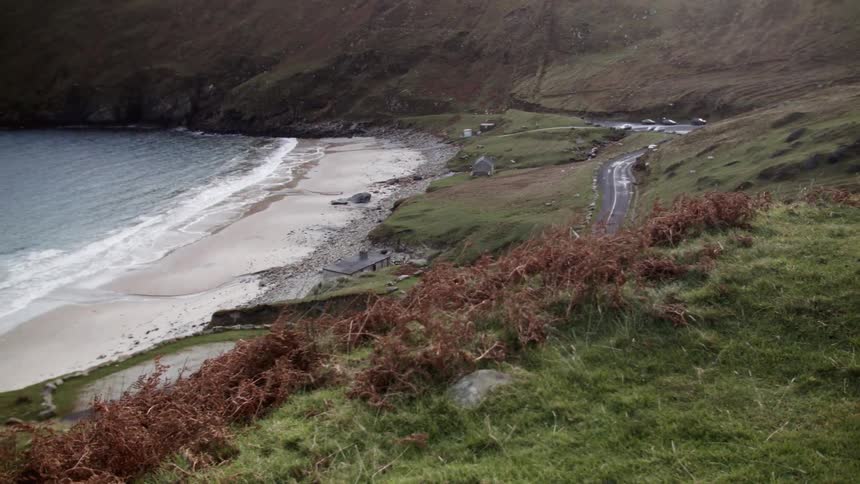 The waves come ashore on a small beach near a road