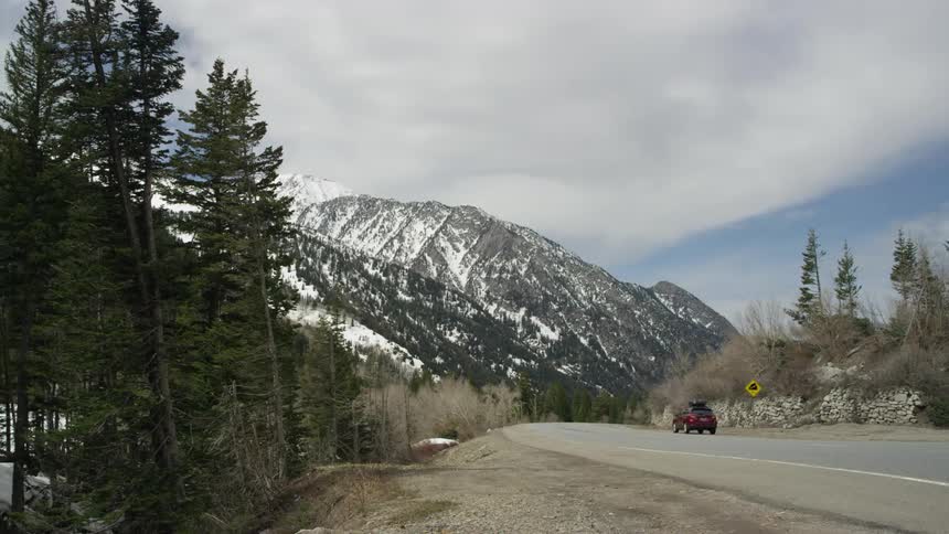 A car drives towards a snow covered mountain ahead