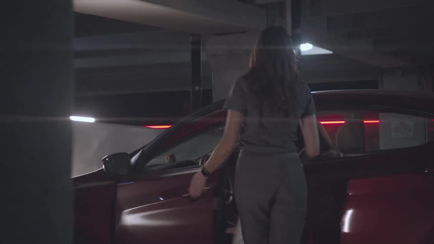 Before getting into her car a woman removes her coat