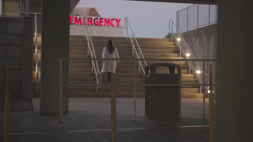 Medical professional walking up stairs from parking garage to emergency room