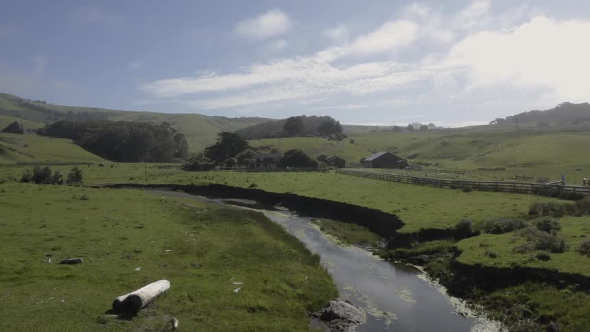 The view of a creek surrounded by grasslands