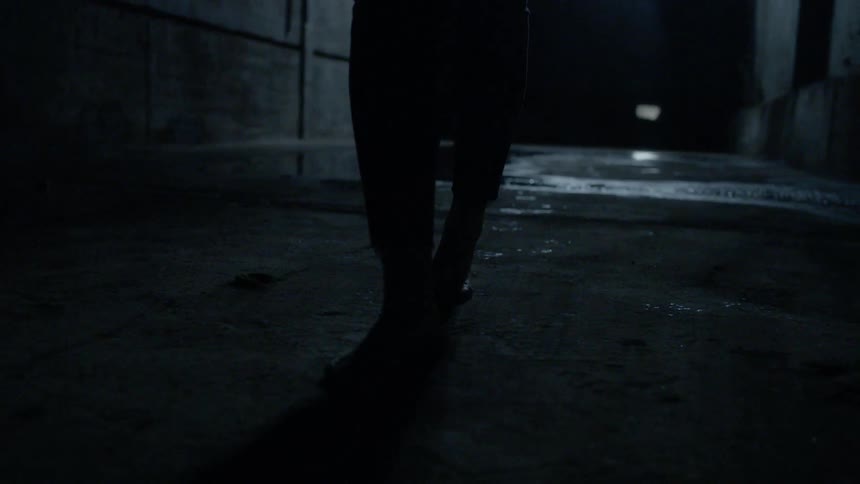 A person is walking on the concrete in a dark alley