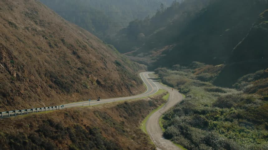 Two people ride a motorcycle on a mountain highway