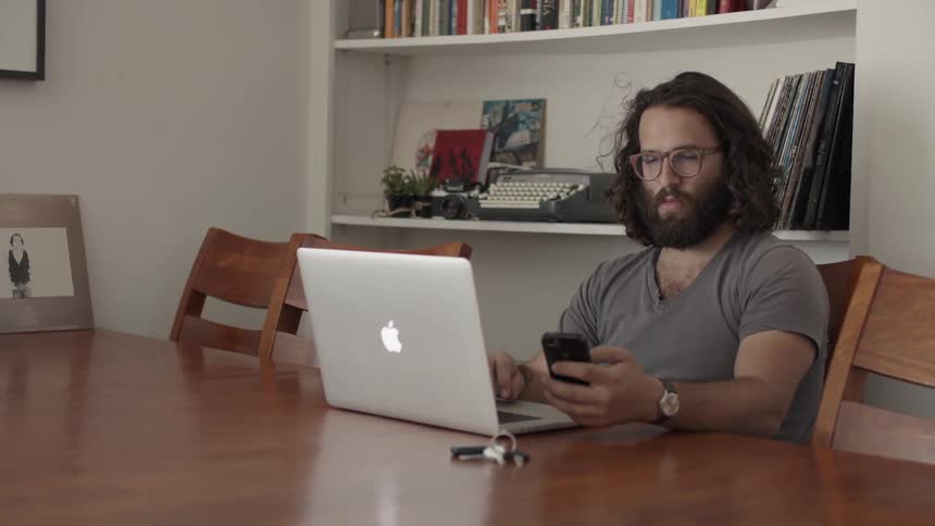 A man sits at a table and works on a laptop