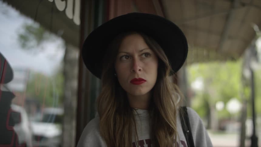 Woman wearing a black hat standing outside a shop on a city street