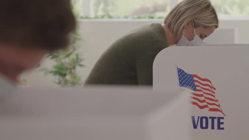 Two people are voting in booths