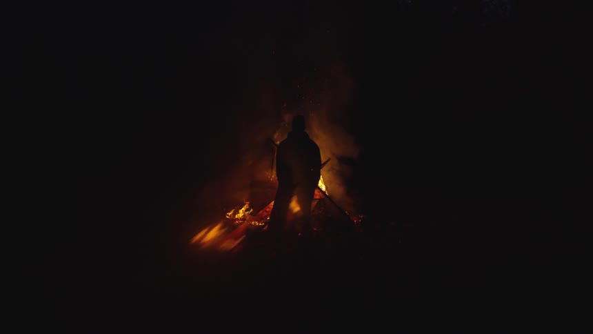 During the night time a person is standing next to a bonfire