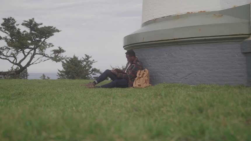 A man sits beside a building and reads