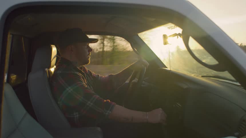 A man is driving his vehicle through the countryside at dusk