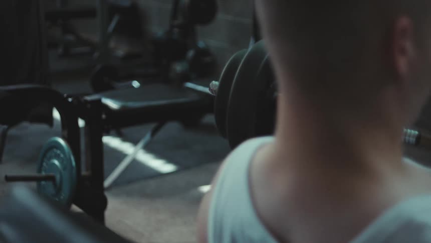 A white male is lifting weights in an empty gym