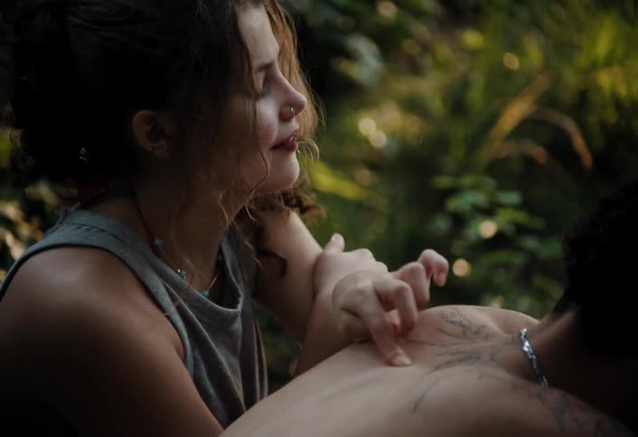 Woman touching and scratching a mans shoulder tattoos in a forest