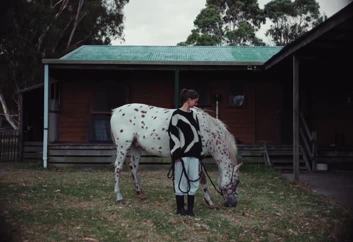 A woman watches her hose eat grass