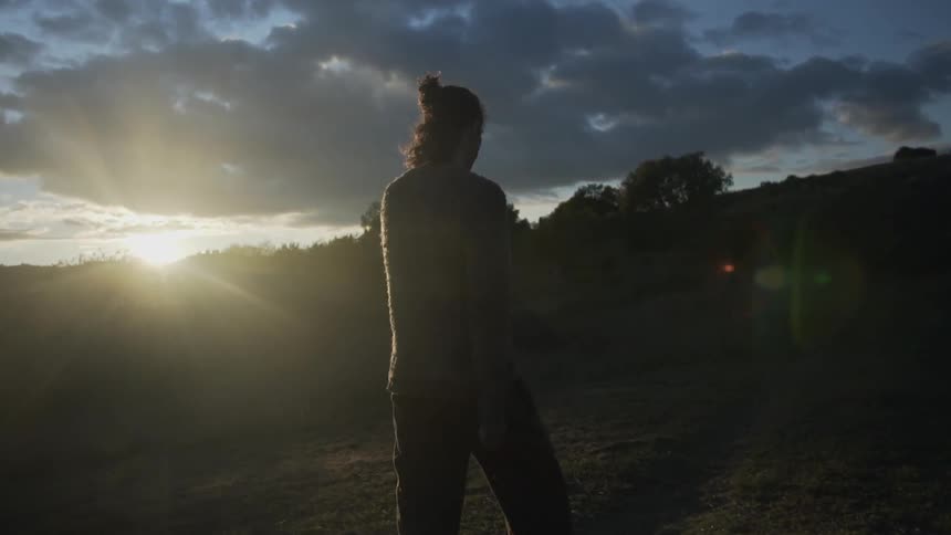 A man is walking in a natural setting at dawn