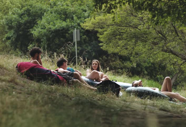 Teenagers hanging out in the wilderness on inner tubes talking and smoking pot