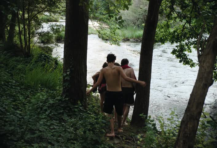 A group of teenagers are hanging out by the stream