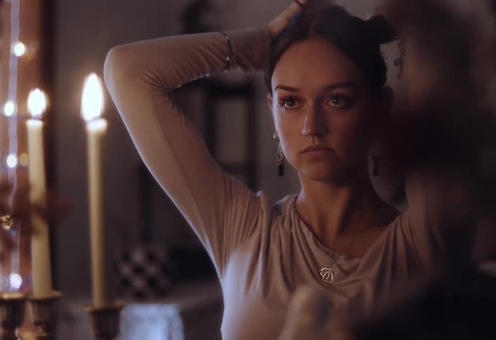 A woman is looking in the mirror and doing her hair