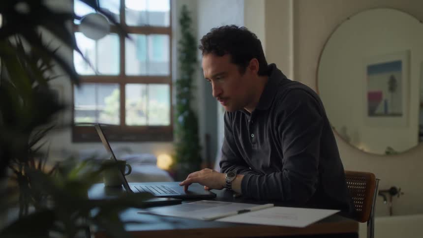 A man is typing on his laptop while sitting at home
