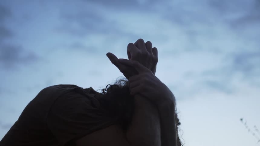 A man lays his head in his arms outside at dusk