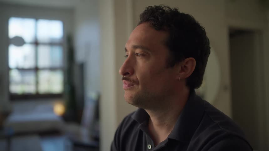 Man is sitting in his house and smiling to himself