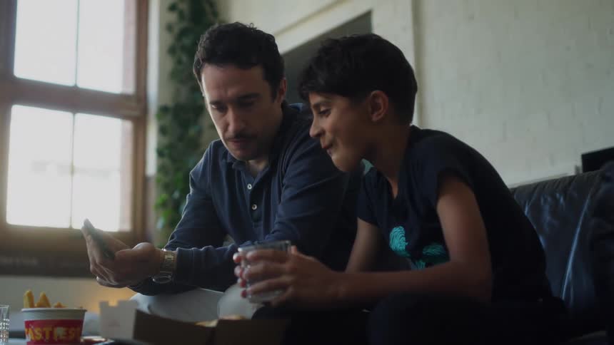 A father shows his son something on his cell phone