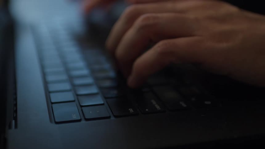 A person is typing fast on a laptop computer