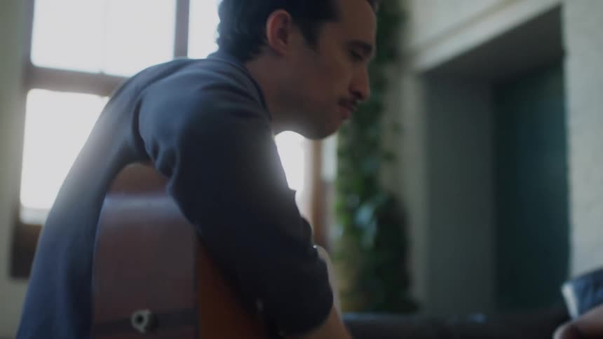 A father is teaching his son how to play the guitar instrument