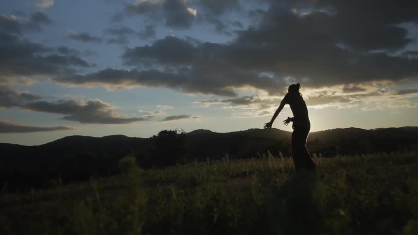 A man dancing at dusk in an open field