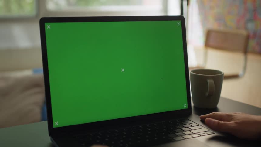 Person sits at a table in front of a laptop in their home during the daytime
