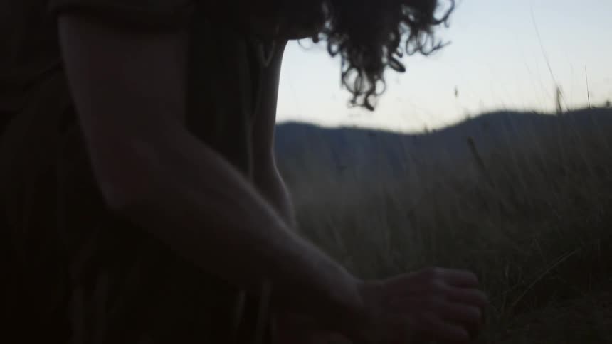 A person slowly lifts their head near some tall grass