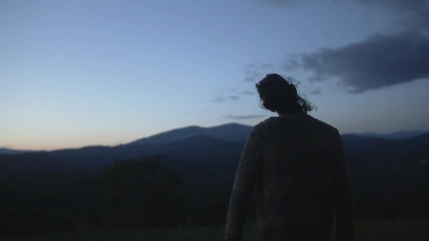 A woman looks over the horizon at dawn stretching her neck
