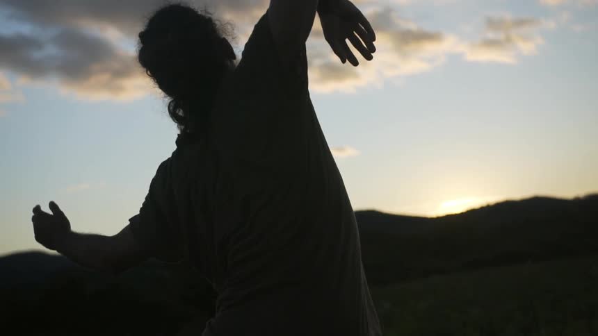 A man is stretching at sunset doing martial arts poses