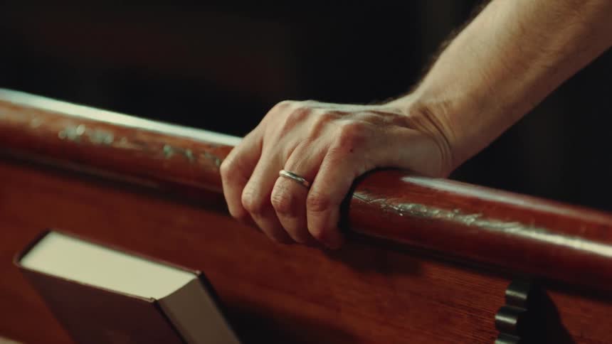 A man leans on a pew in the church