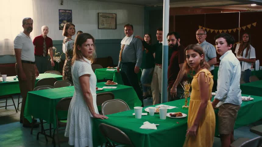 People attending a birthday party turn to look in the same direction with frowns