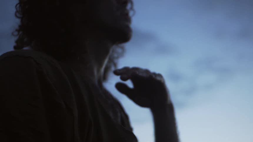 A person has his hand up as he looks up at dawn